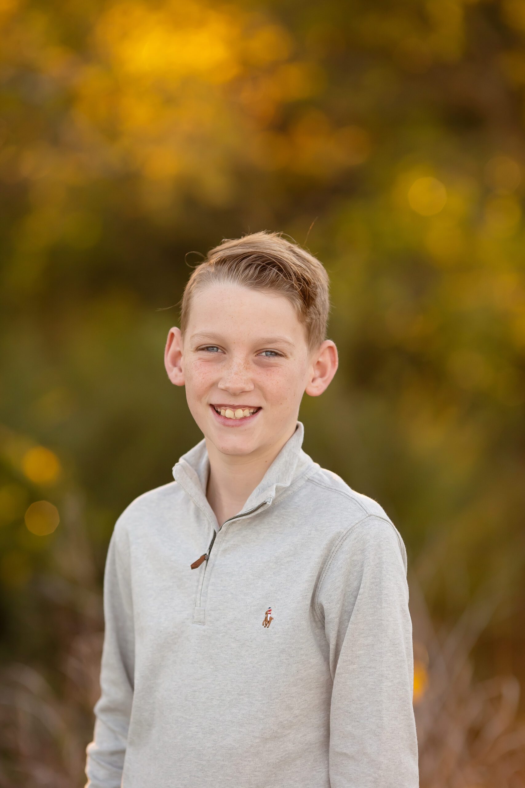 Boy in grey quarter-zip sweater smiling at Highlight Ultra Mini Session