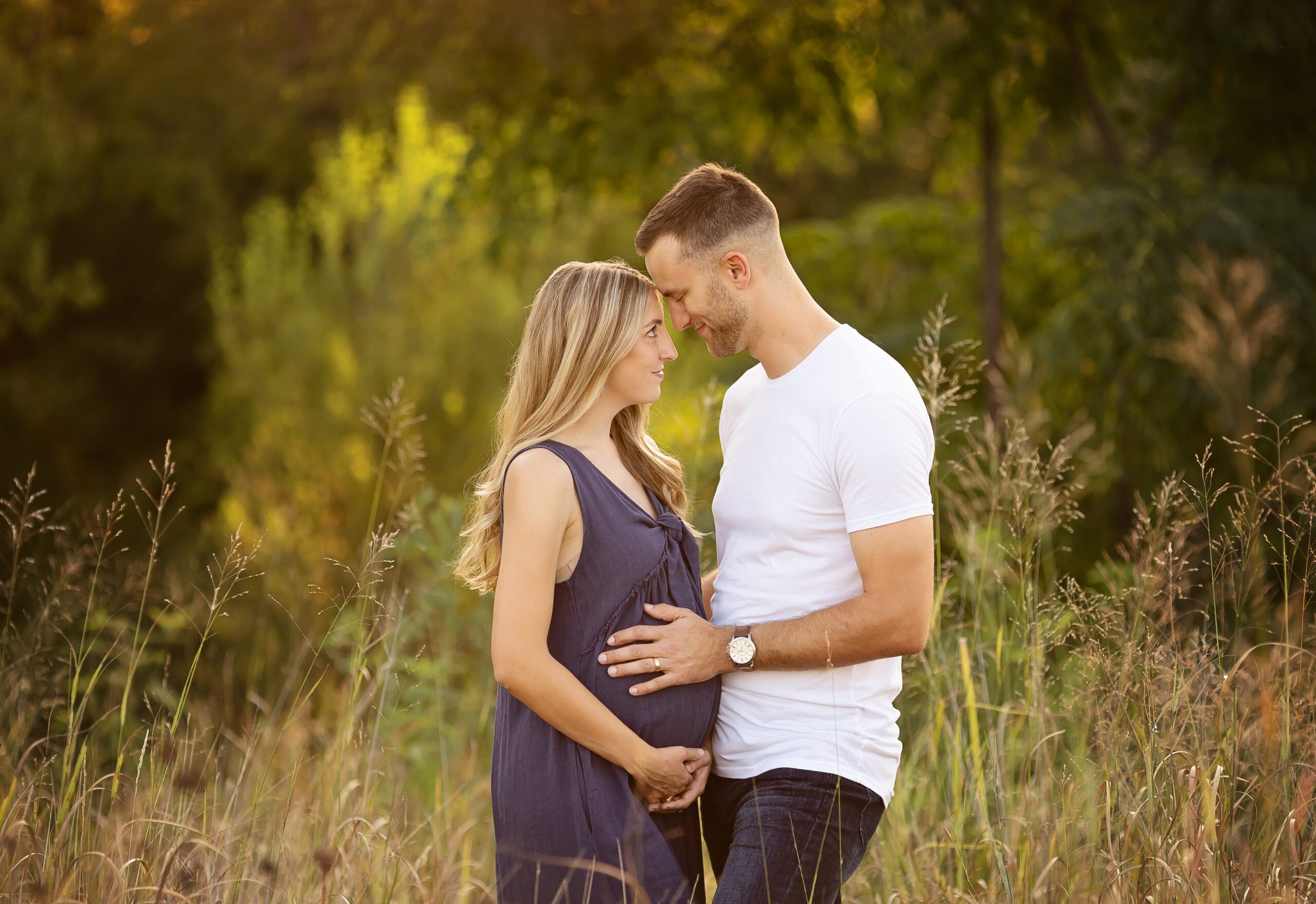 Expecting couple during golden hour maternity session in College Station, Texas, standing in a grassy field.