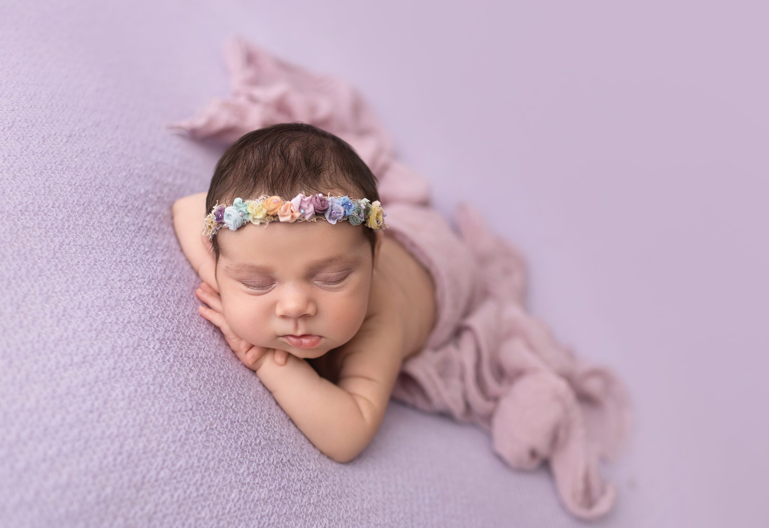 Newborn baby girl Brooklyn sleeping on a soft pink backdrop with a pearl and lace headband during her College Station, TX newborn session.