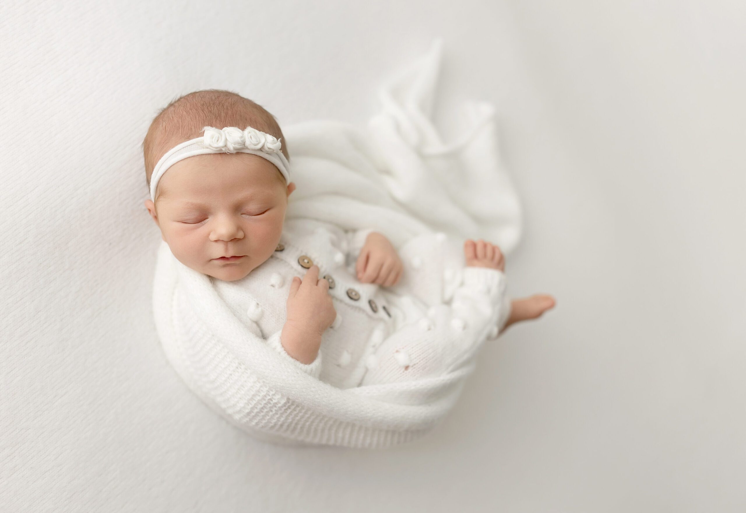 Newborn baby girl wrapped in white knit outfit during College Station photography session