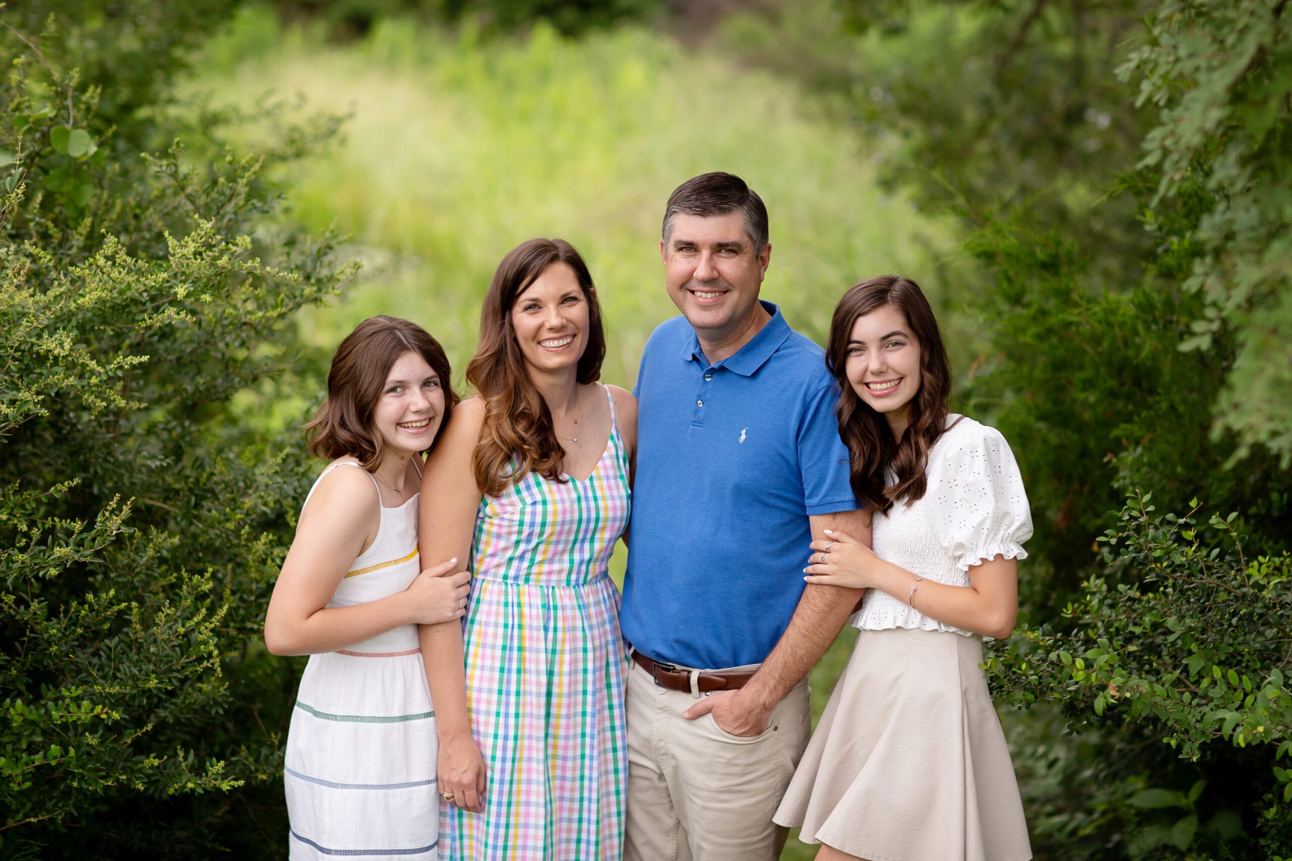 The West family smiling together outdoors during their summer family photography session in Bryan College Station TX