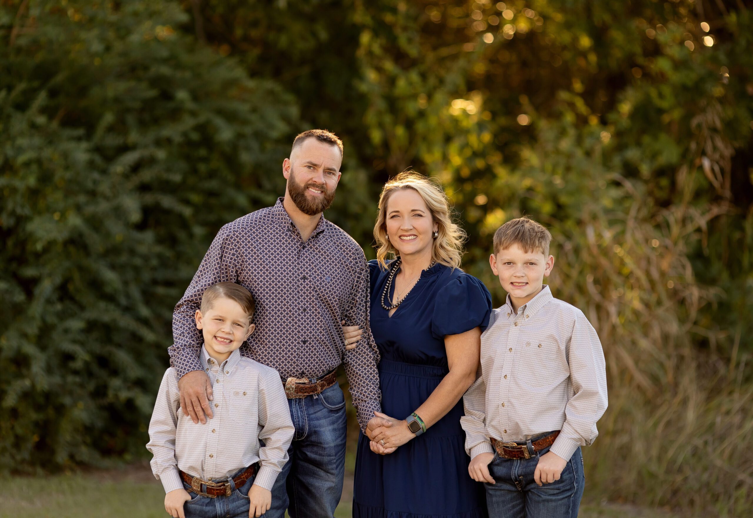 The Thomas family standing together outdoors during their fall family photography session in Bryan College Station TX